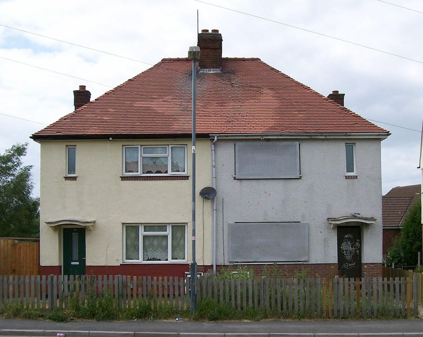 Terraced houses. One appears empty with boarded up windows and doors.