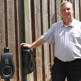 Leader of the council standing next to two electric vehicle charging points