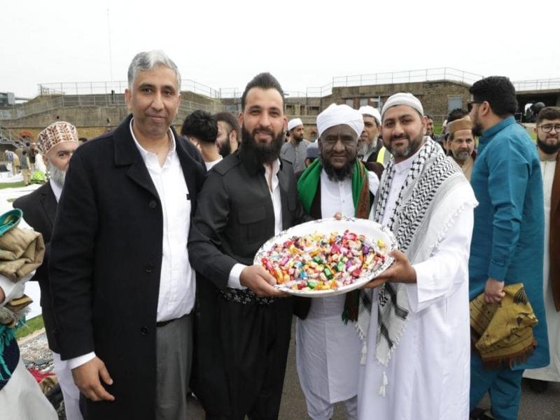 Group of 3 men holding plate of treats as they celebrate Eid