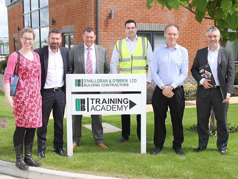 6 people standing in a row behind a sign for O'Halloran & O'Brian Limited training academy