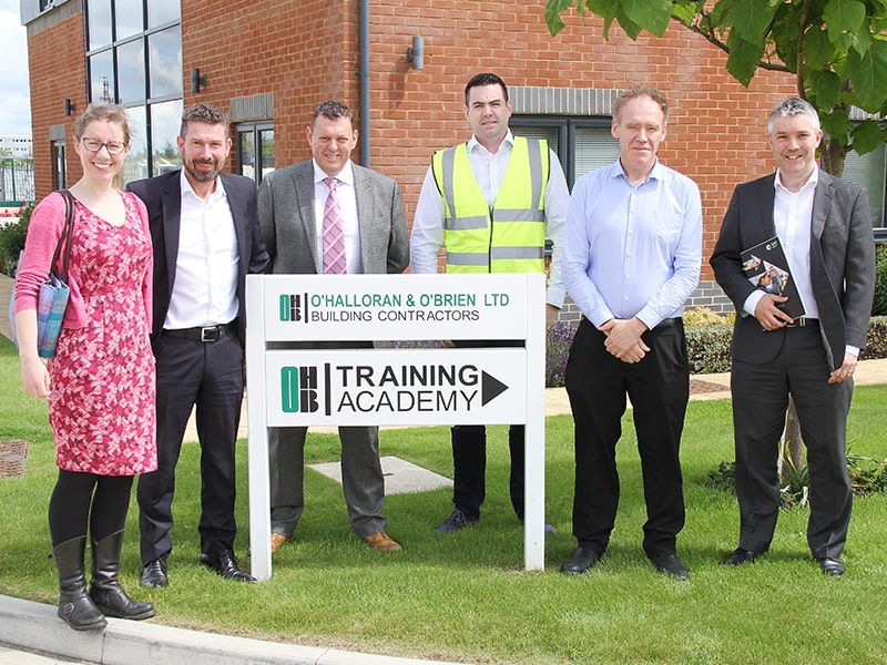 6 people standing in a row behind a sign for O'Halloran & O'Brian Limited training academy