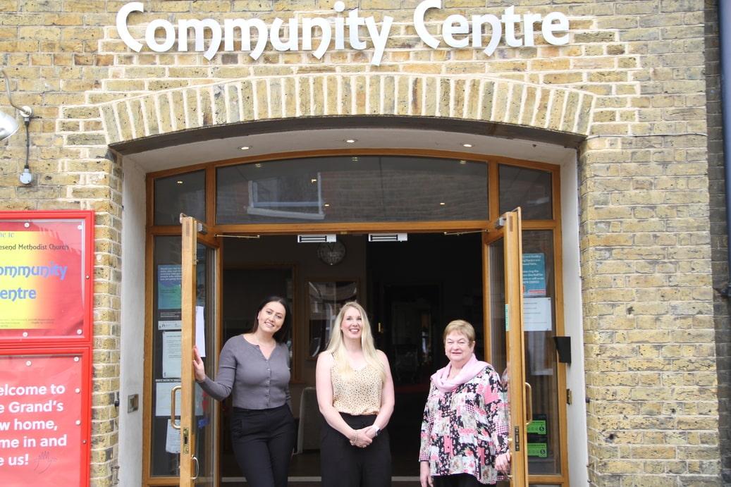 Three people standing in front of open double doors to the community centre