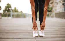 Legs of a woman wearing active wear with her arms leaning in front as she stretches over.