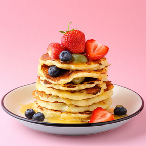 Stack of pancakes with berries and syrup.