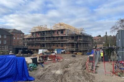 Construction site showing a block of homes being built, the roof beams are on.