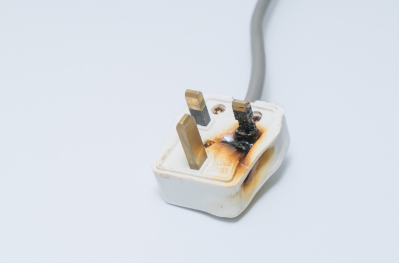 A UK electrical plug showing the underneath with one of the pins with some damage.