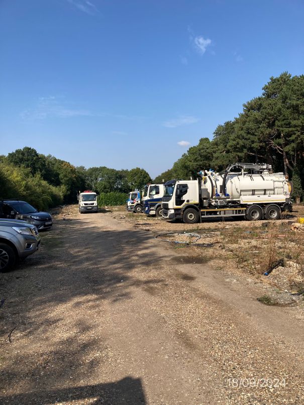 Land being used by a drainage company with large vehicles and cars in view