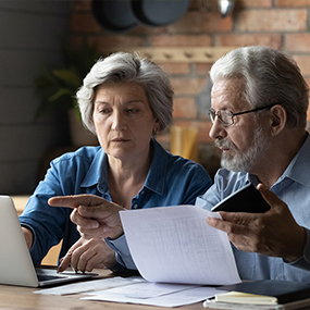 Elderly couple looking at a laptop and energy bills