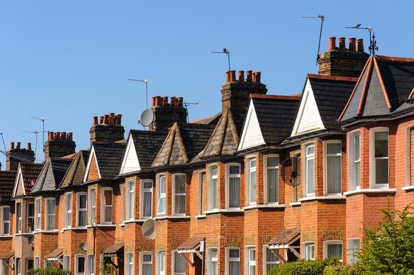 Street of homes in a row at an 45 degree angle, the homes are made of red brick against a blue sky