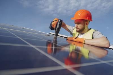 Person installing a solar panel, wearing a hard hat