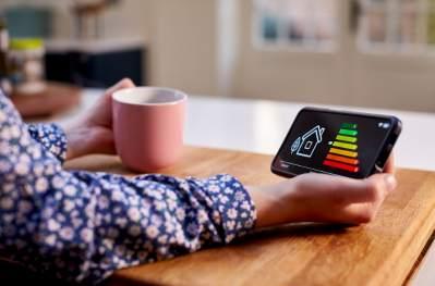 Hand holding a small smart metre showing the energy rating chart