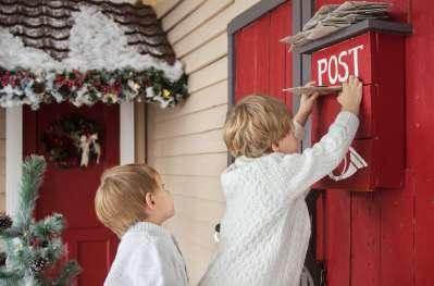 Children placing letters in a red postbox