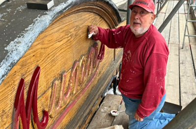 Wooden shopfront being painted 'munns' in deep red